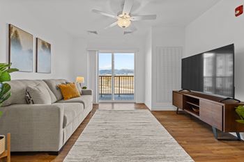 A living room with a grey couch, a television, and a large window with a view of the ocean. at Yellowstone Landing, Montana